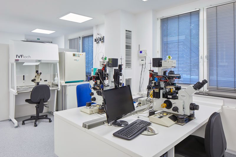 Blik in een laboratorium met pc, microscopen en diverse analyseapparatuur, verdeeld over verschillende werkplekken