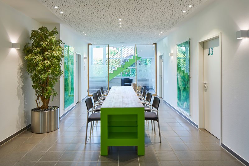 Green-ivf vergaderzaal, lange tafel met stoelen.